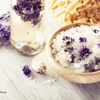 bowl of lavender bath soak with a glass of lavender essential oil