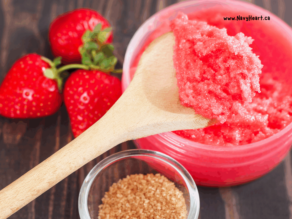 Strawberry sugar scrub on a spoon next to brown sugar and strawberries