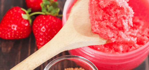 Strawberry sugar scrub on a spoon next to brown sugar and strawberries