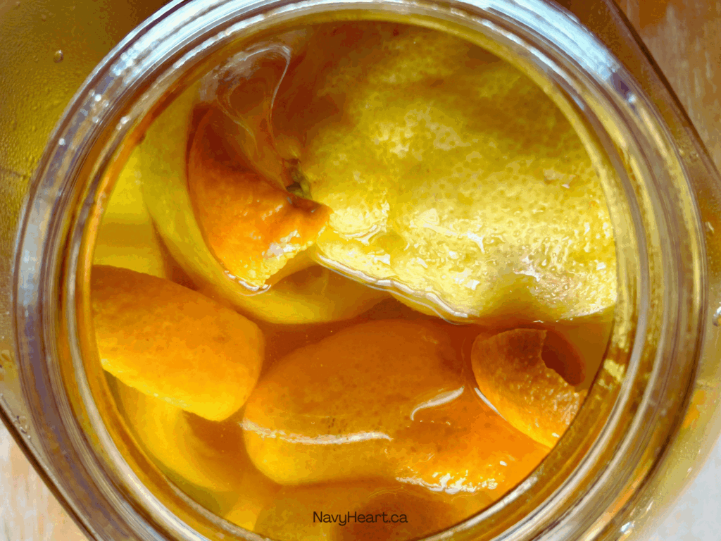 glass jar of lemon and orange peels soaking for a bathroom cleaner